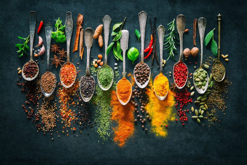 Ayurvedic herbs and spices in whole and powdered form on spoons.
