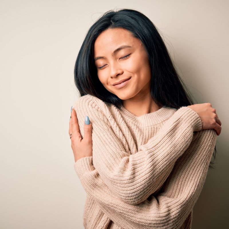 woman wrapping her arms around to hug herself