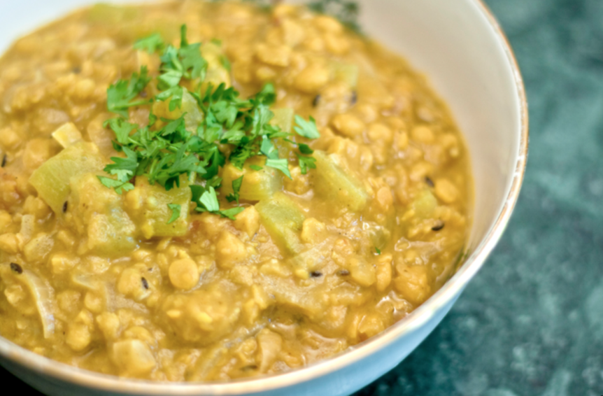 Kitchari with turmeric in white bowl and cilantro garnish.