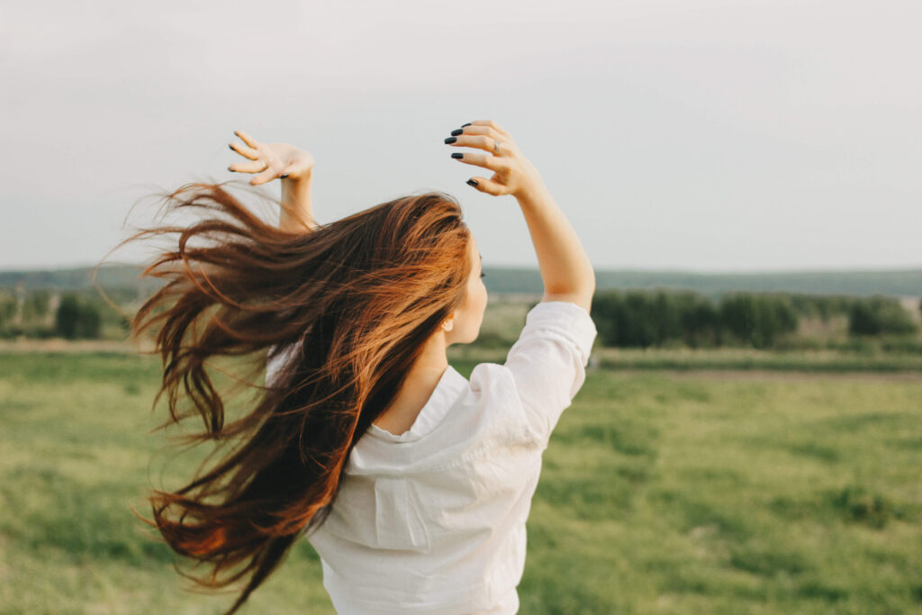 Woman in nature with white shirt and long, healthy hair.