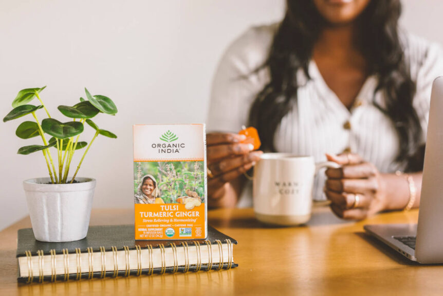 Turmeric tea box on book and women with turmeric tea mug at laptop