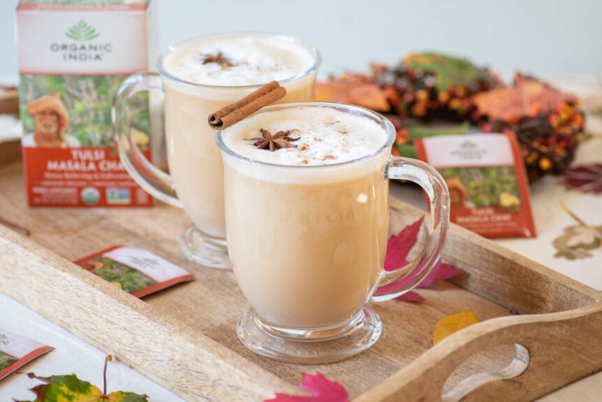 Classic Chai Tea latte with Tulsi in a clear mug with steamed milk and clove and cinnamon garnish.