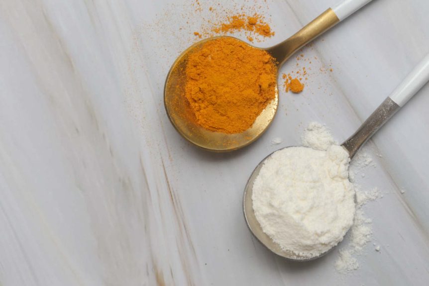 Collagen vs turmeric powdered supplements on spoon upon marble table