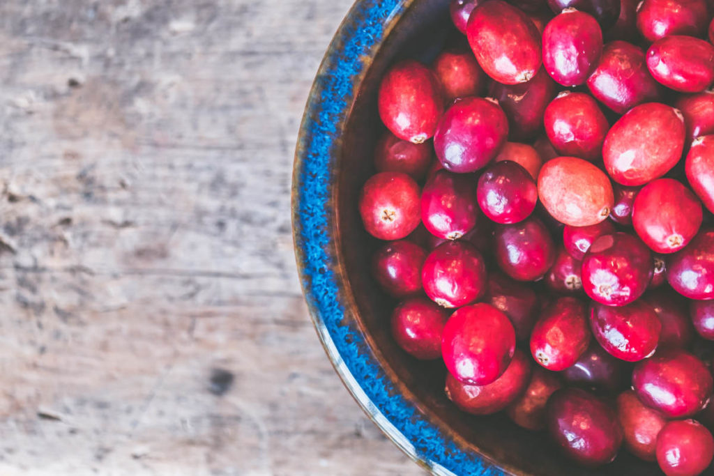 Blue ceramic bowl on a wooden table filled with fresh cranberries for kidney health.