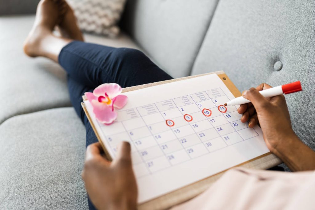 Woman marking her calendar with her monthly cycle to help maximize her cycle syncing practice.