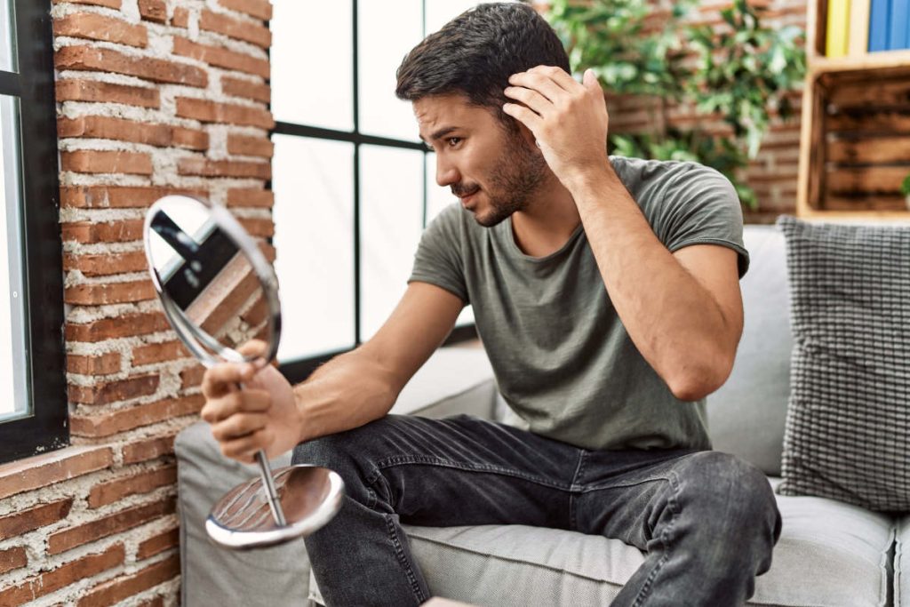 Man looking in mirror at hair gotu kola hair loss benefits