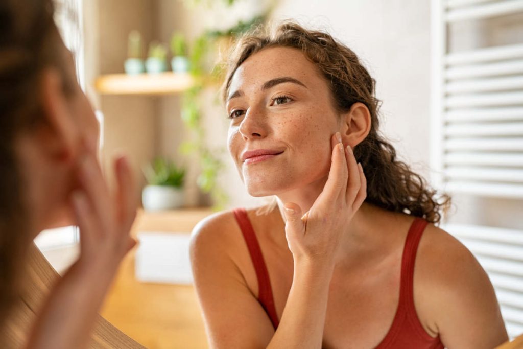 Woman looking at her clear skin in the mirror