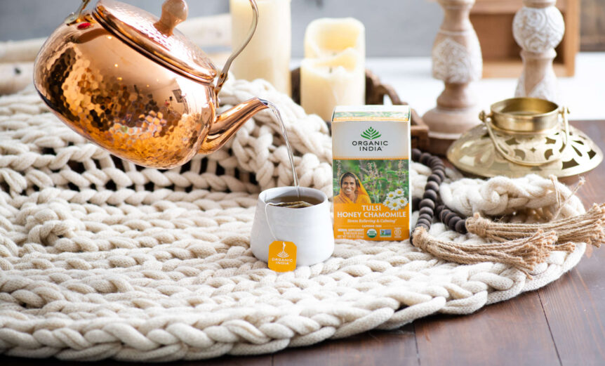 Herbs for peace tulsi honey chamomile tea on blankets with copper tea kettle.