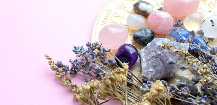 Herbs for the zodiac with crystals and star chart on a soft pick table.