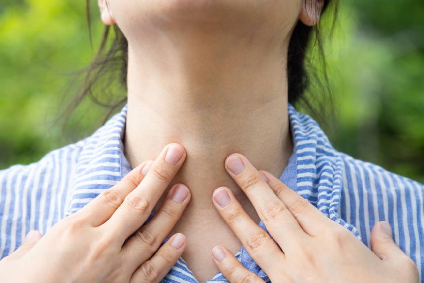 Woman taking herbs for thyroid and putting hands to her thyroid outside