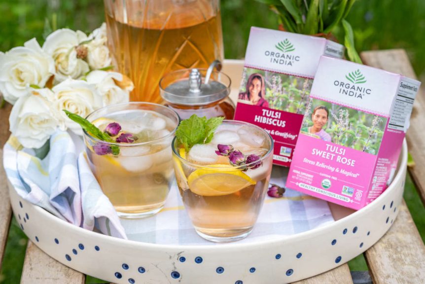 Hydrating floral iced tea on tray for backyard picnic with 2 glasses and pitcherful