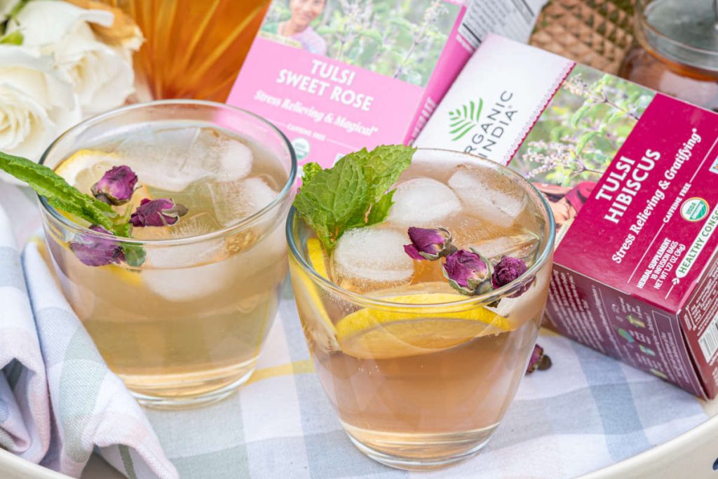 Hydrating floral iced tea on tray for backyard picnic with 2 glasses and pitcherful