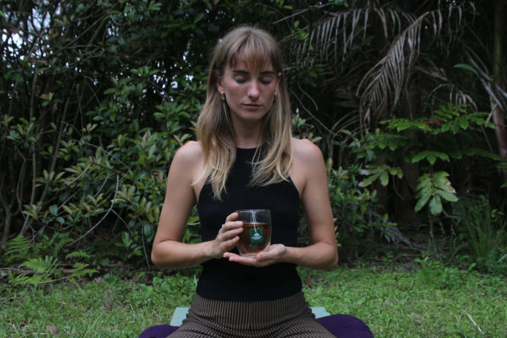 Woman drinking tulsi tea while meditating, 2 grounding practices