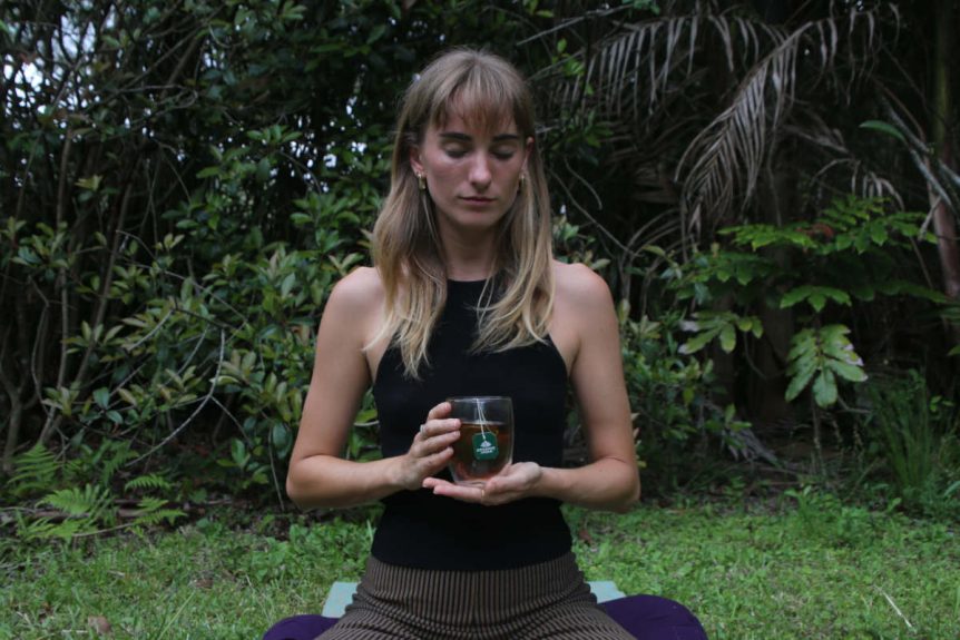 Woman drinking tulsi tea while meditating, 2 practices to increase serotonin naturally