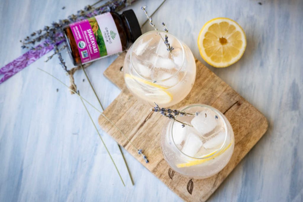 sparkling lavender lemonade in rounded glasses with shatavari and lemon garnish.