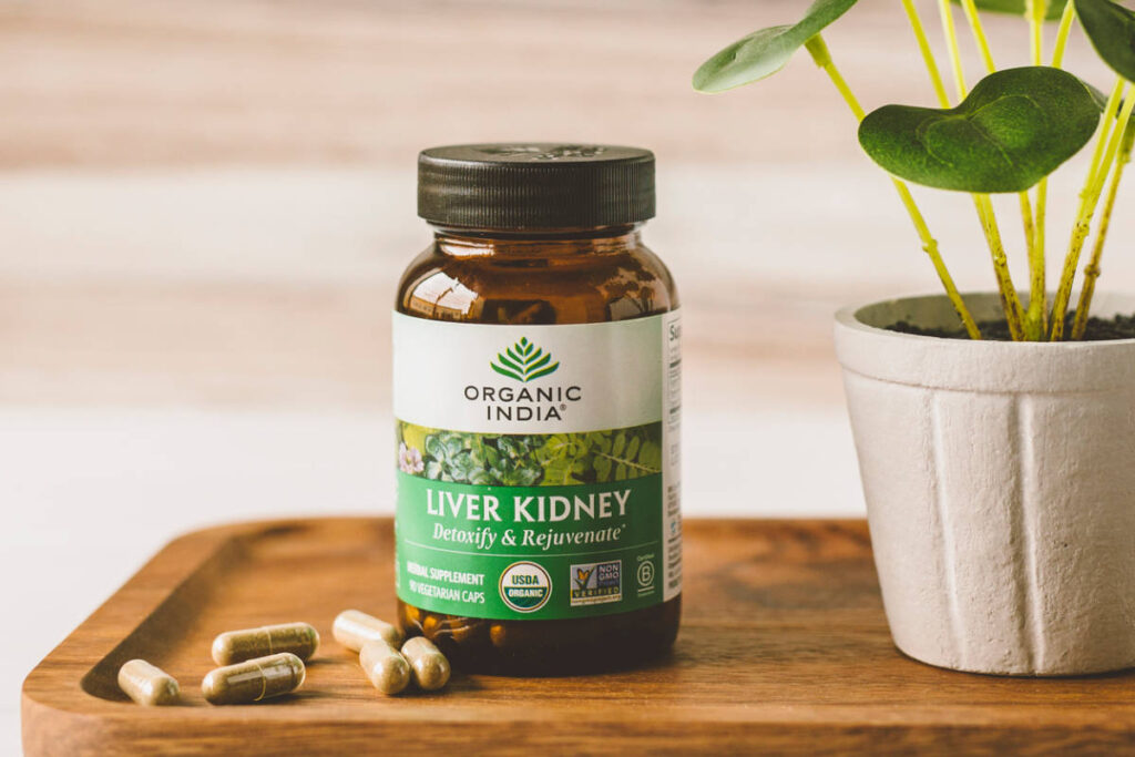 Liver Kidney supplement with herbs for kidney health on wooden platter near plant.