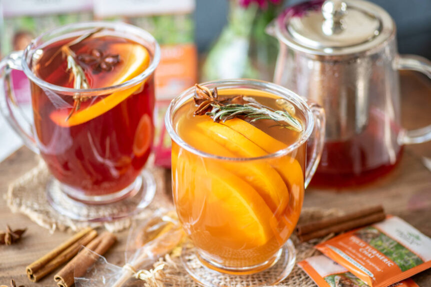 Mulled tea in clear tea mug garnished with orange and cinnamon.