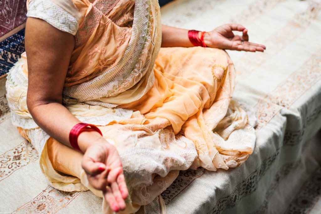 Woman in sari sitting in yoga meditation with mudra