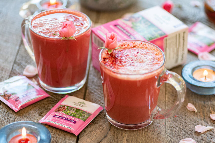 Rich hot pink potion latte in clear mug with fresh rose petals and candle.