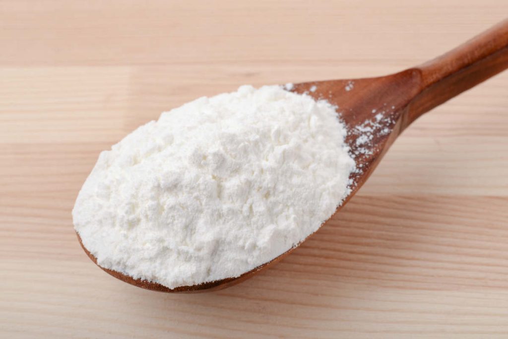 Dextrin powder in a wood spoon on a wood table.
