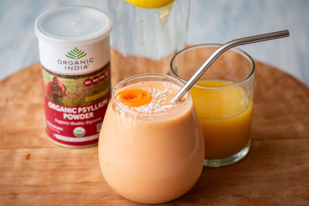 Psyllium husk powder in water, juice and smoothie on wooden cutting board.