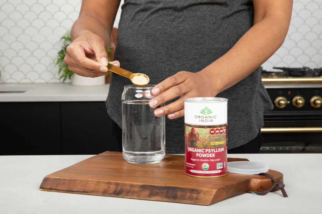 Woman stirring psyllium powder into water in beautiful kitchen with marble countertops