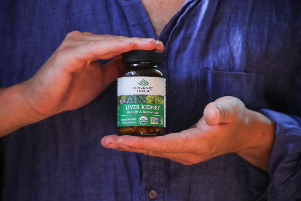 Man in blue button down shirt holding liver kidney capsules in glass jar