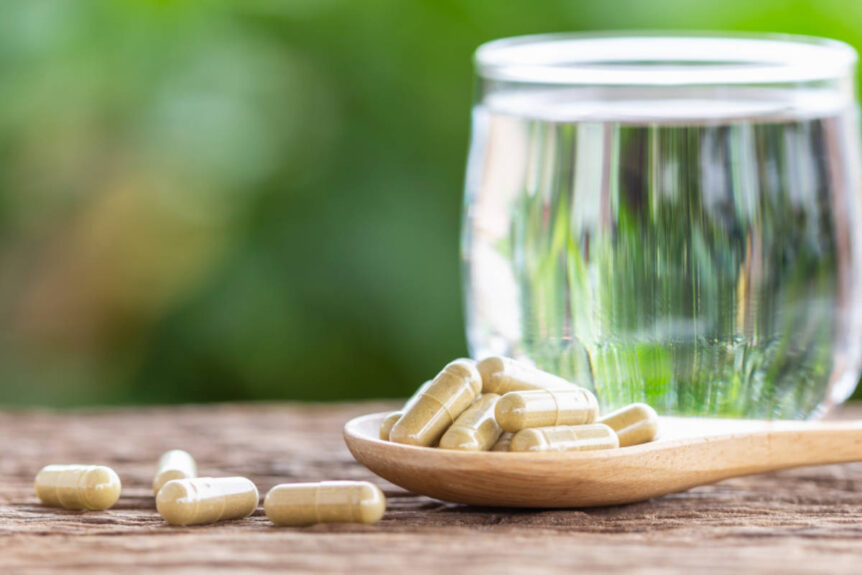 Senna supplement capsules on wooden table with glass of water