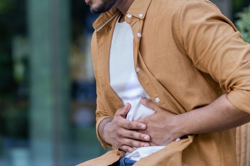 Man experiencing stress and digestion issues on bench outside office building.
