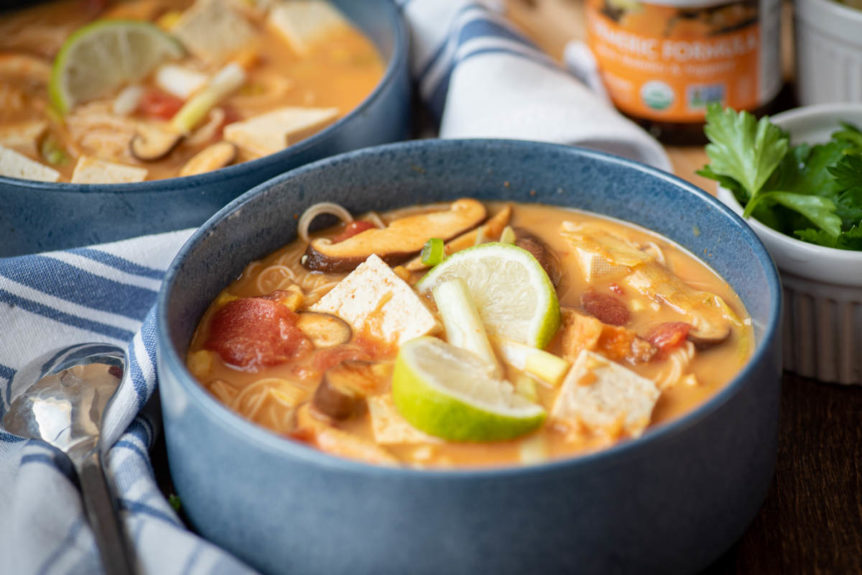 Blue bowl of tom yum soup with mushrooms, veggies, creamy herb broth and lime for dinacharya lunch.