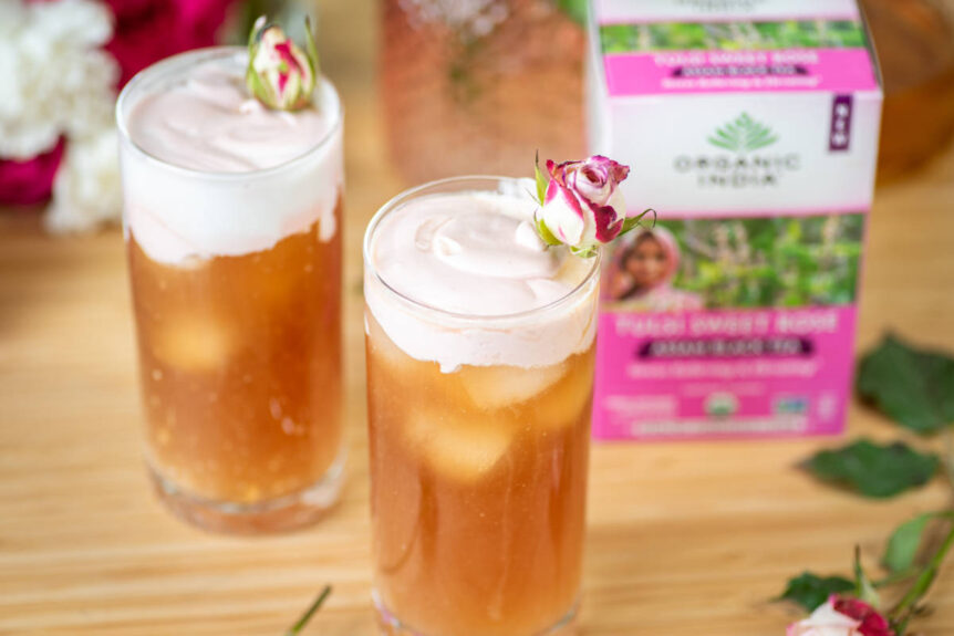 Tulsi sweet rose cold foam tea latte in clear glass over ice with rose garnish.