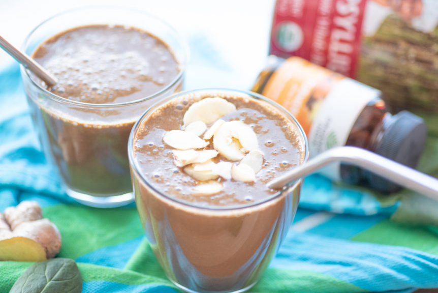 Chocolate turmeric ginger shake in clear glass with stainless steel straw.