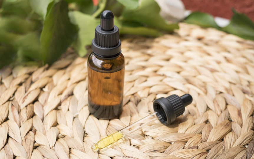 Tincture bottle and dropped full of andrographis extract on a straw table cloth with plant